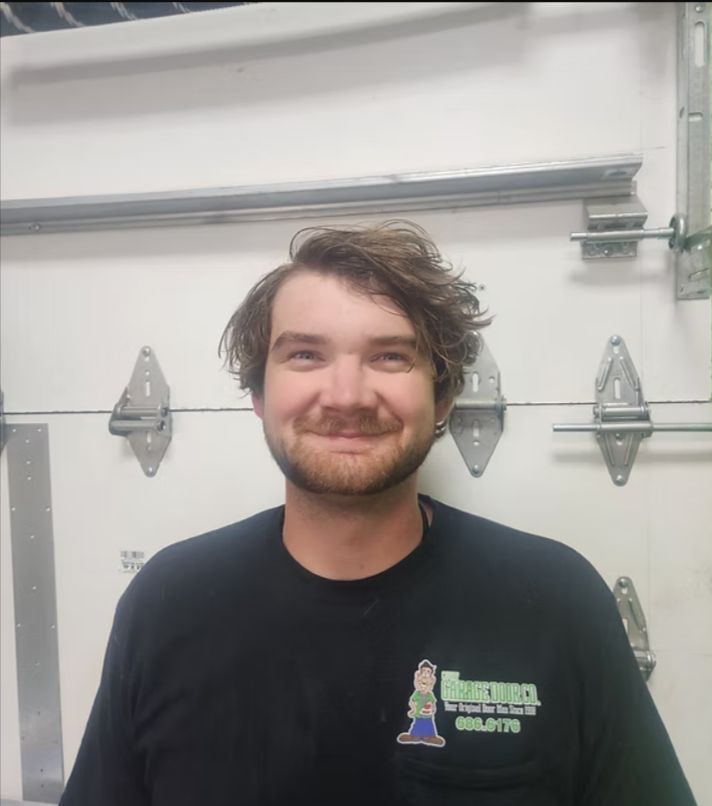 Smiling person in a black shirt standing in front of a garage door