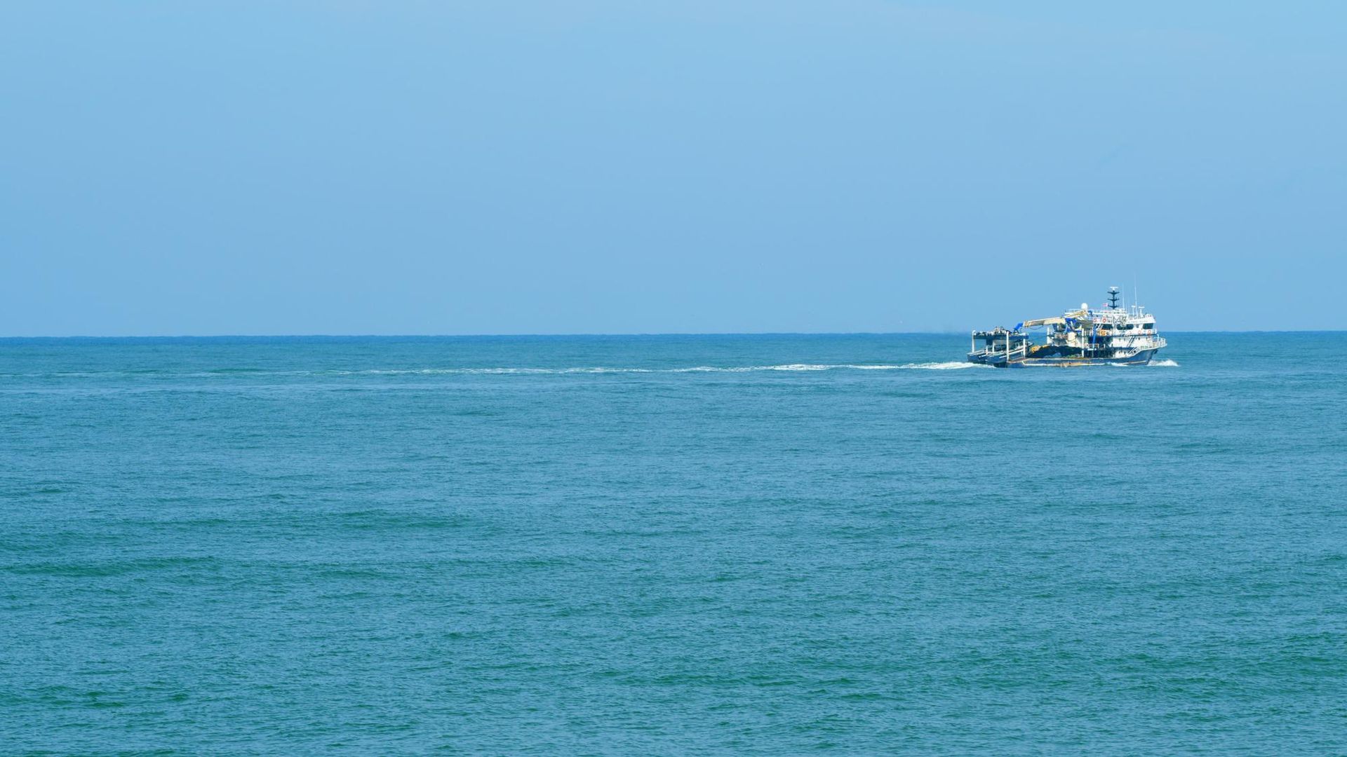 Small boat on a blue ocean under a clear sky
