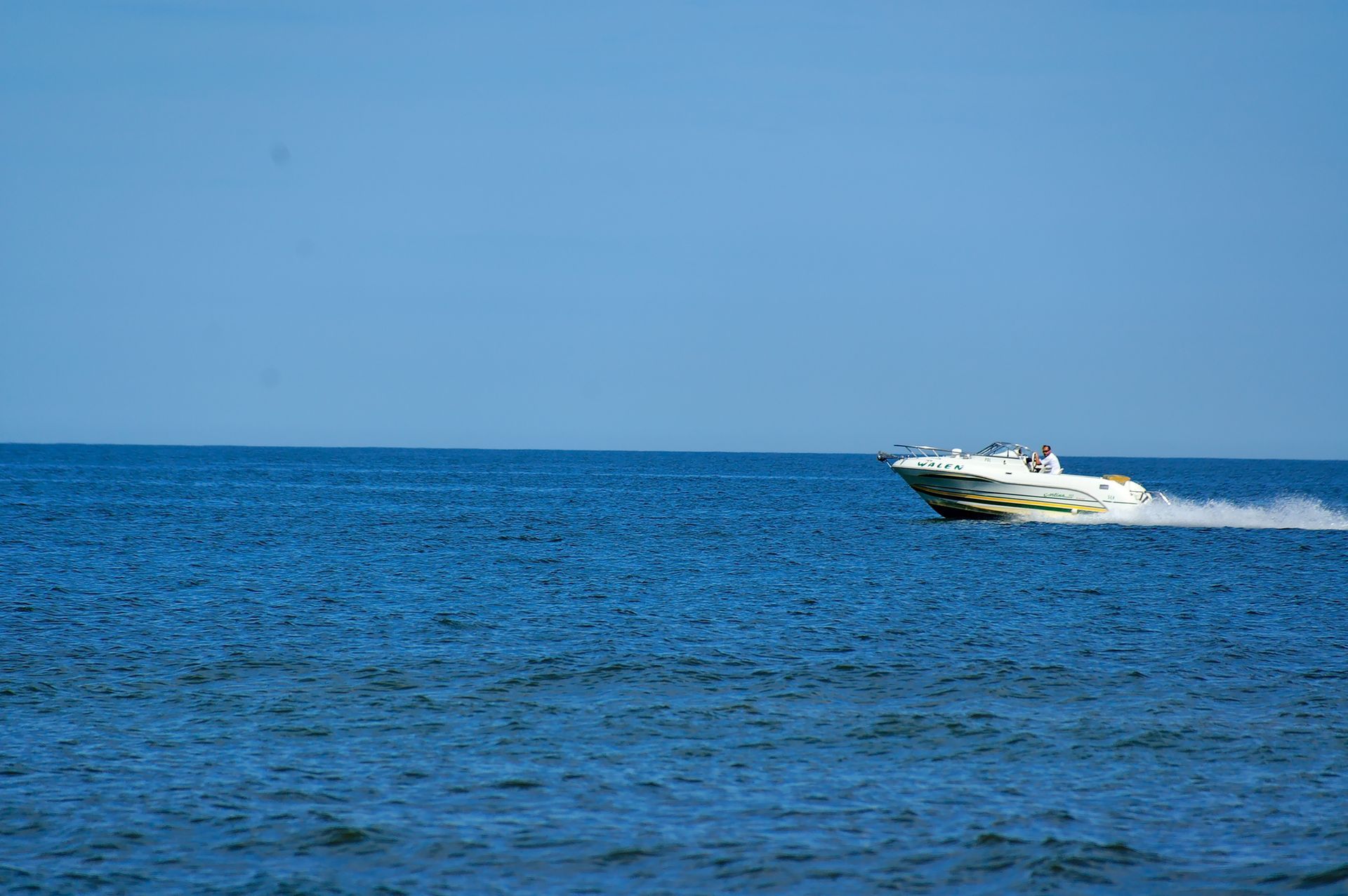 Speedboat skimming across a calm blue sea under a clear sky