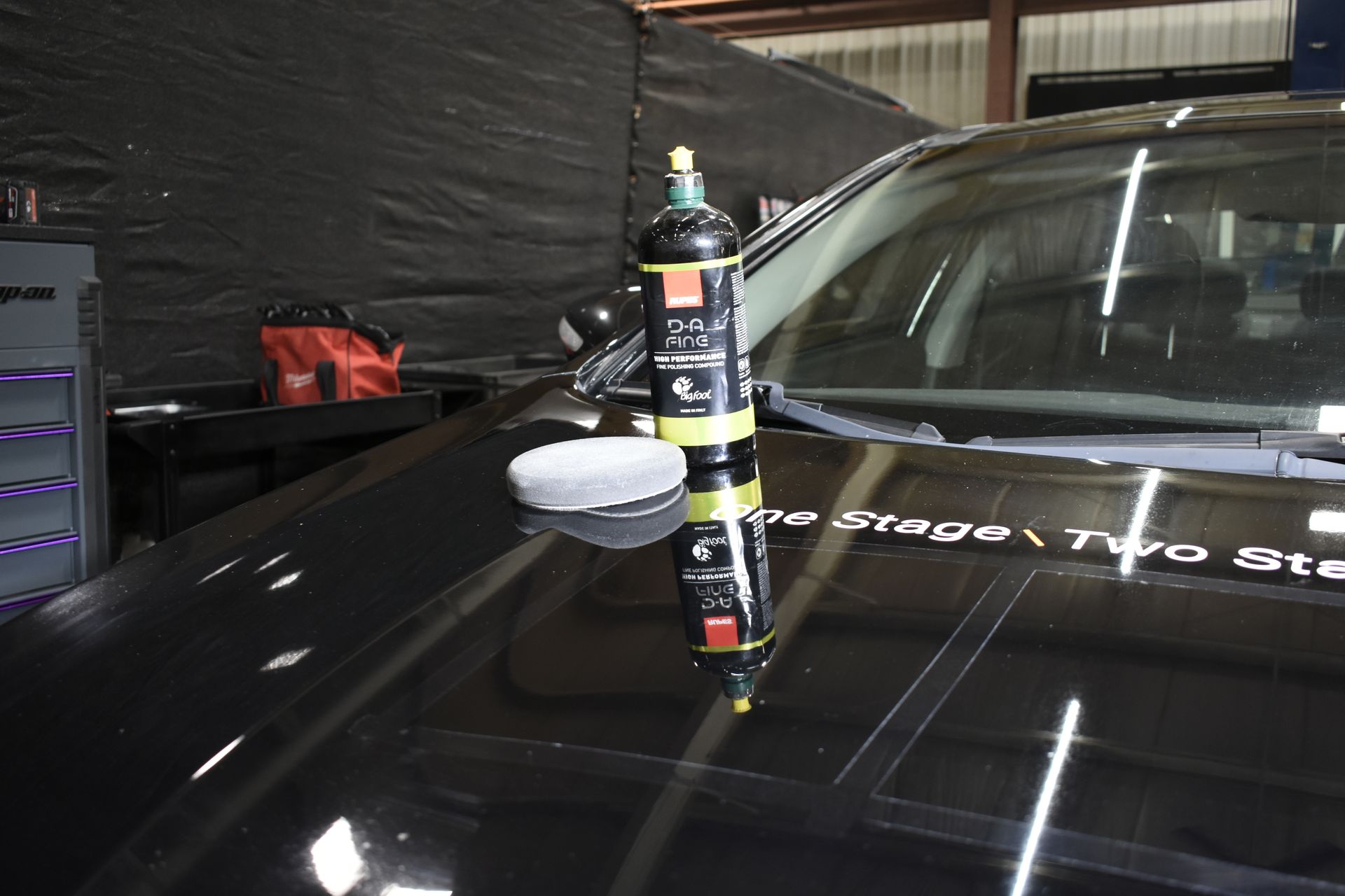 Black car hood with polishing products and a reflection.
