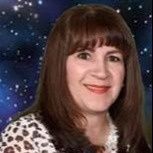A woman with long brown hair is smiling in front of a starry sky.