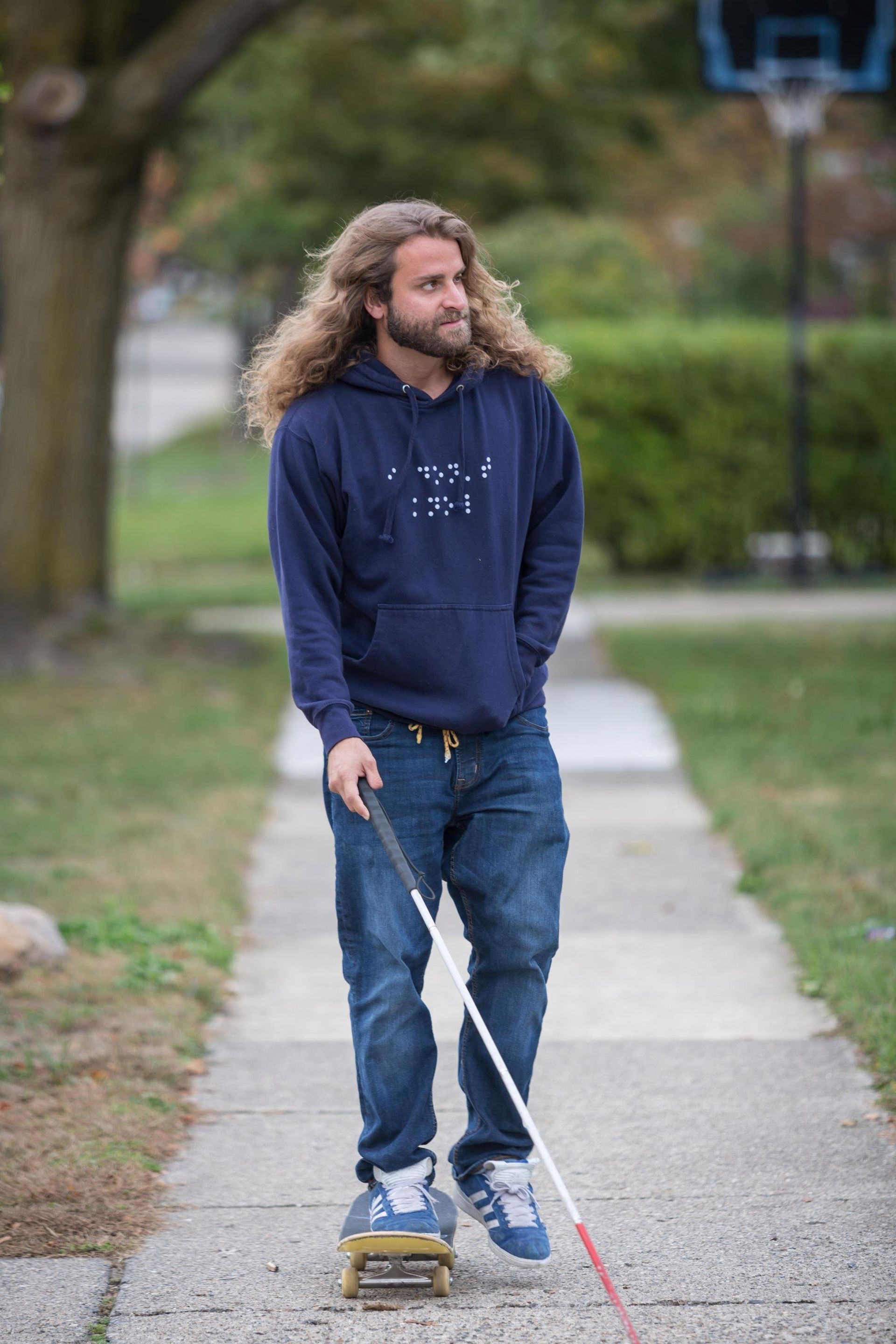 Dan Mancina skates his way down a suburban sidewalk with cane for guidance.