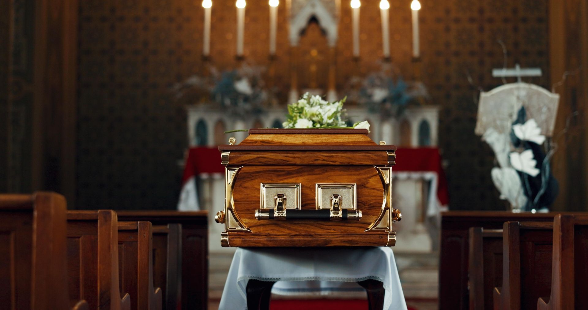 A coffin with white roses and green carnations on it.