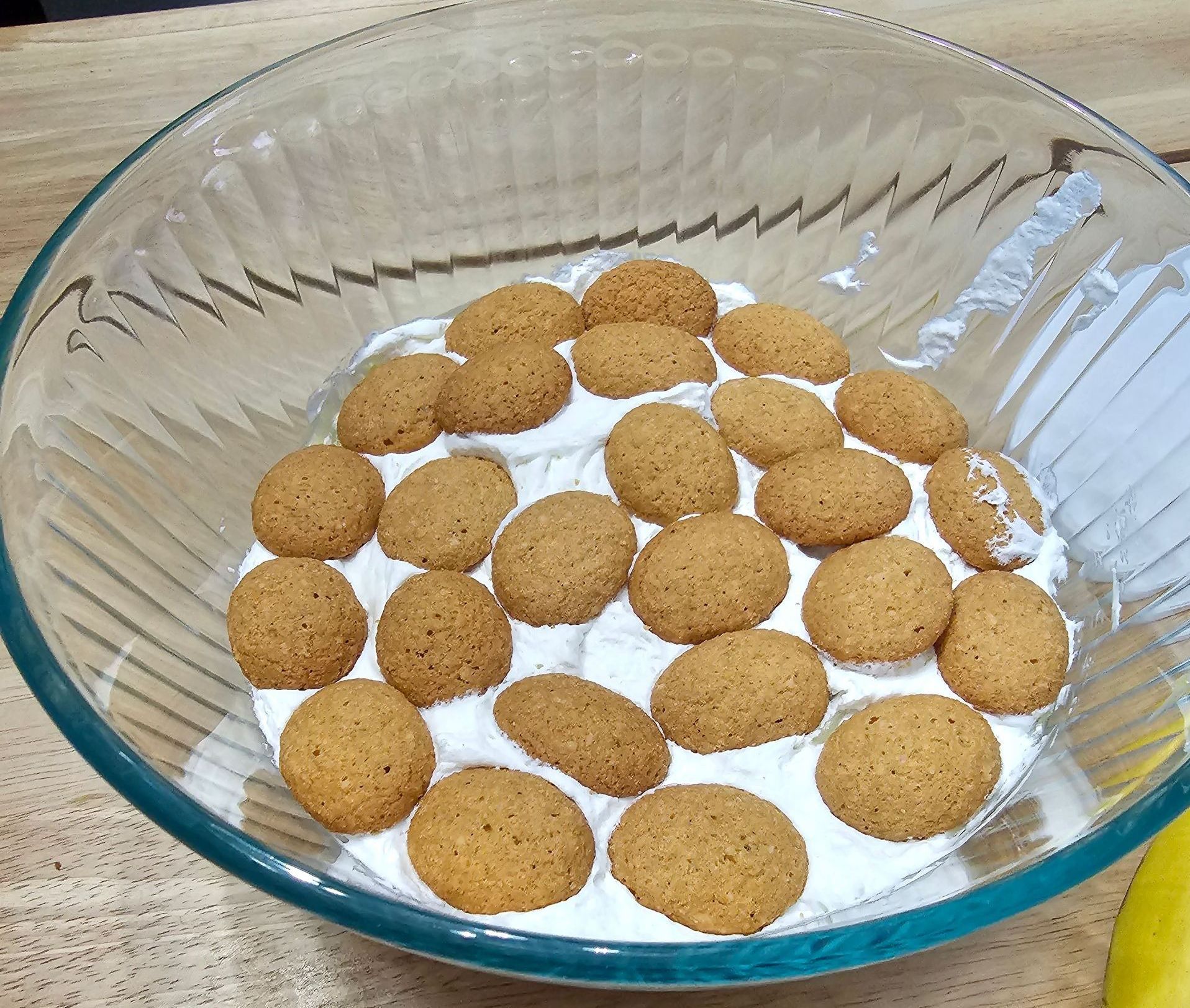 Glass bowl with cookies arranged on a layer of white cream.
