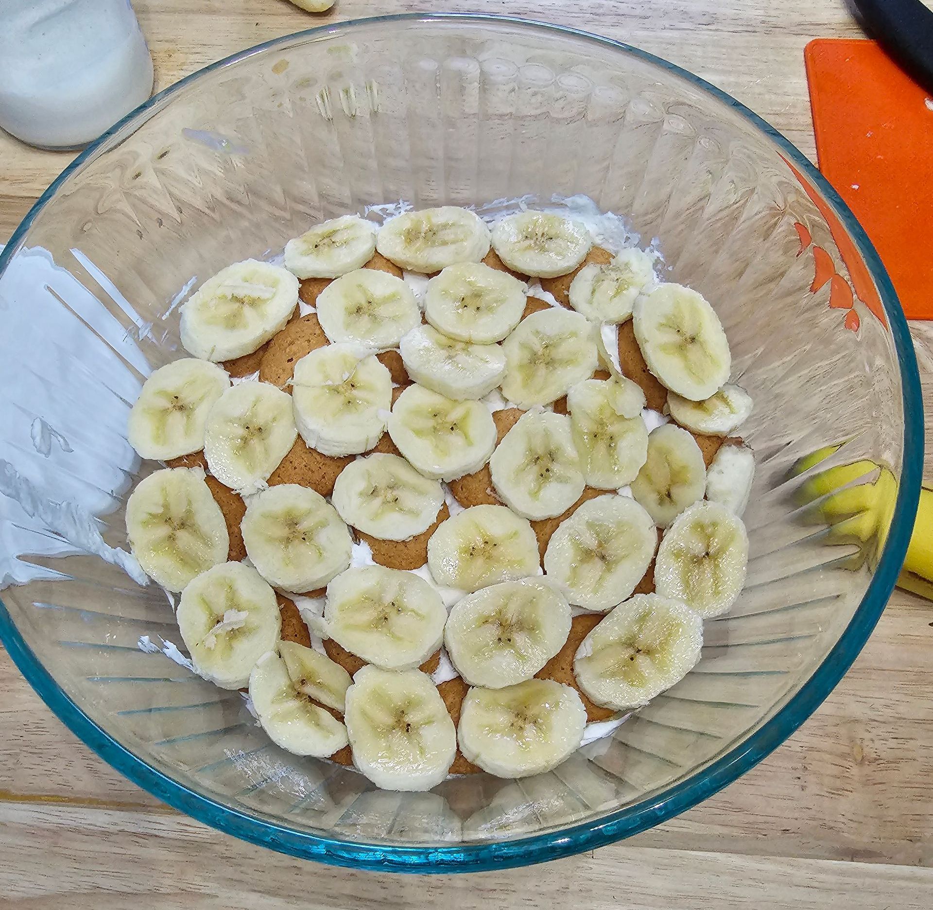 Sliced bananas on a bed of dessert with white topping in a clear glass bowl.