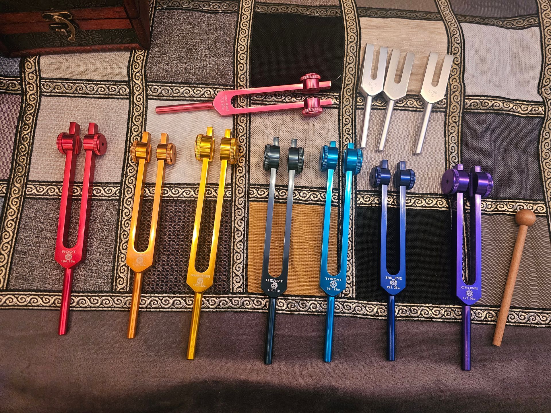Colorful tuning forks arranged on a patterned surface, some with mallets.