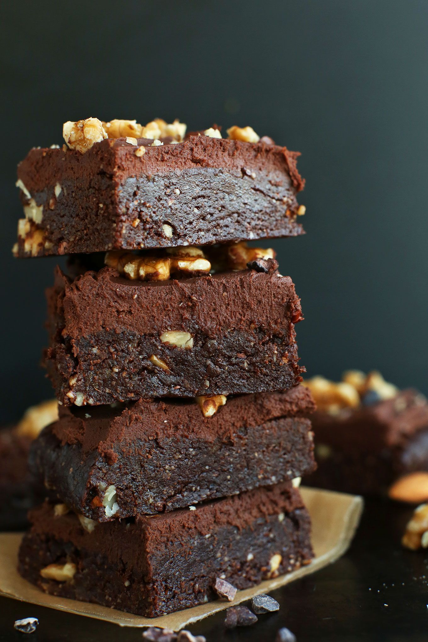 Stack of chocolate brownies with walnuts on a black background.