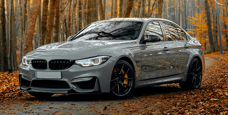 Gray BMW sedan parked on a leaf-covered forest road in autumn | Kars Performance