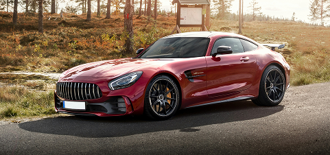 Red sports coupe parked on a road beside a wooded hillside in autumn. | Kars Performance
