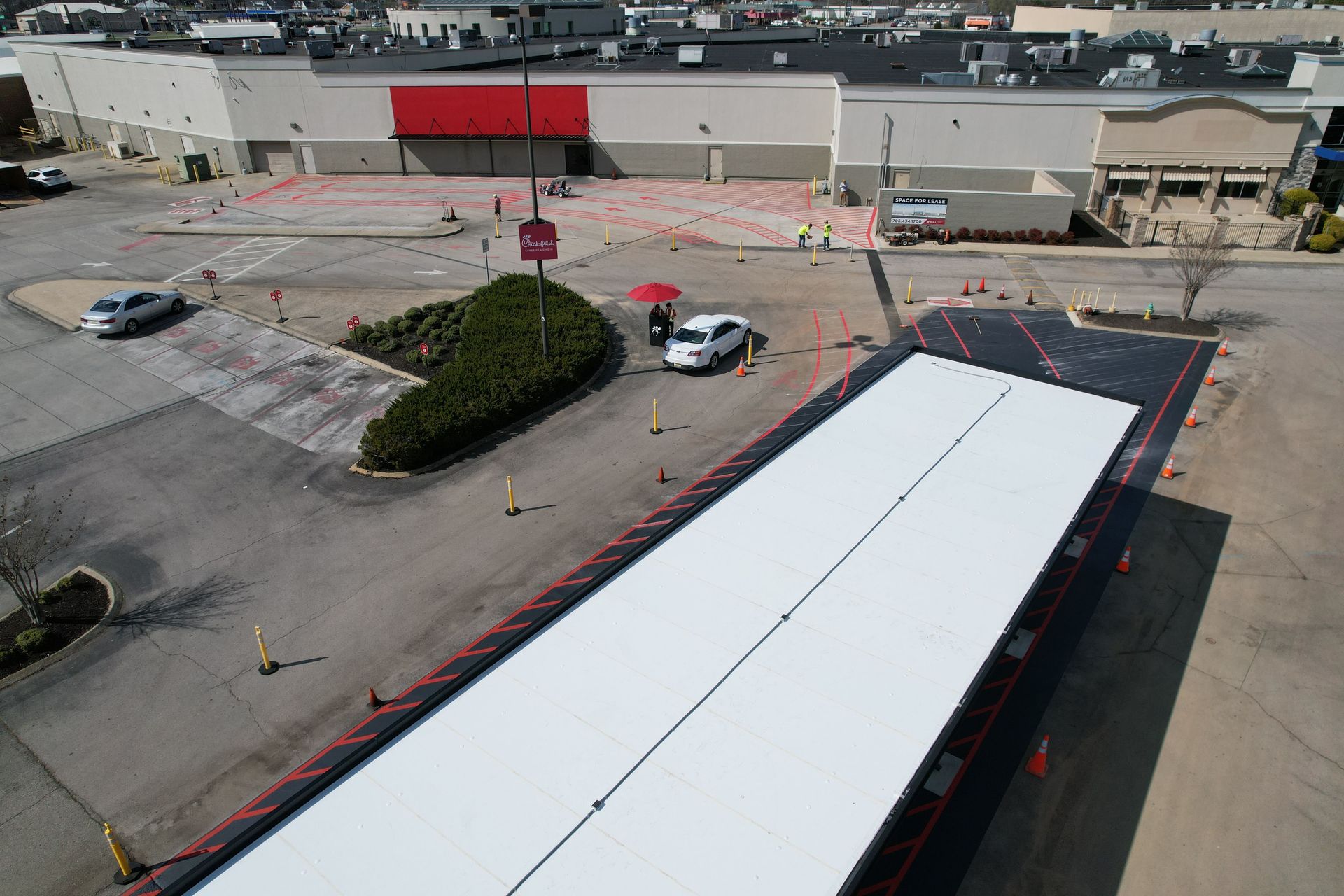 Aerial view of a truck loading area with a white trailer, a few cars, and a building with a red awning.