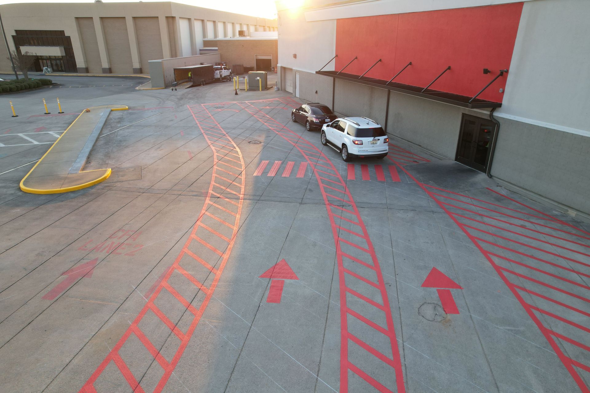 Marked loading dock with red directional arrows and a white car beside a warehouse wall