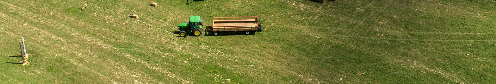 An aerial view of a tractor cutting grass in a field.