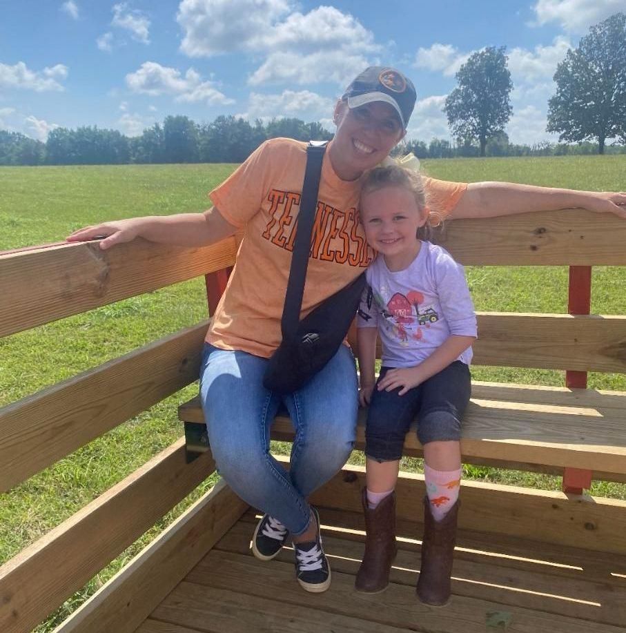 A woman and a little girl are sitting on a wooden bench