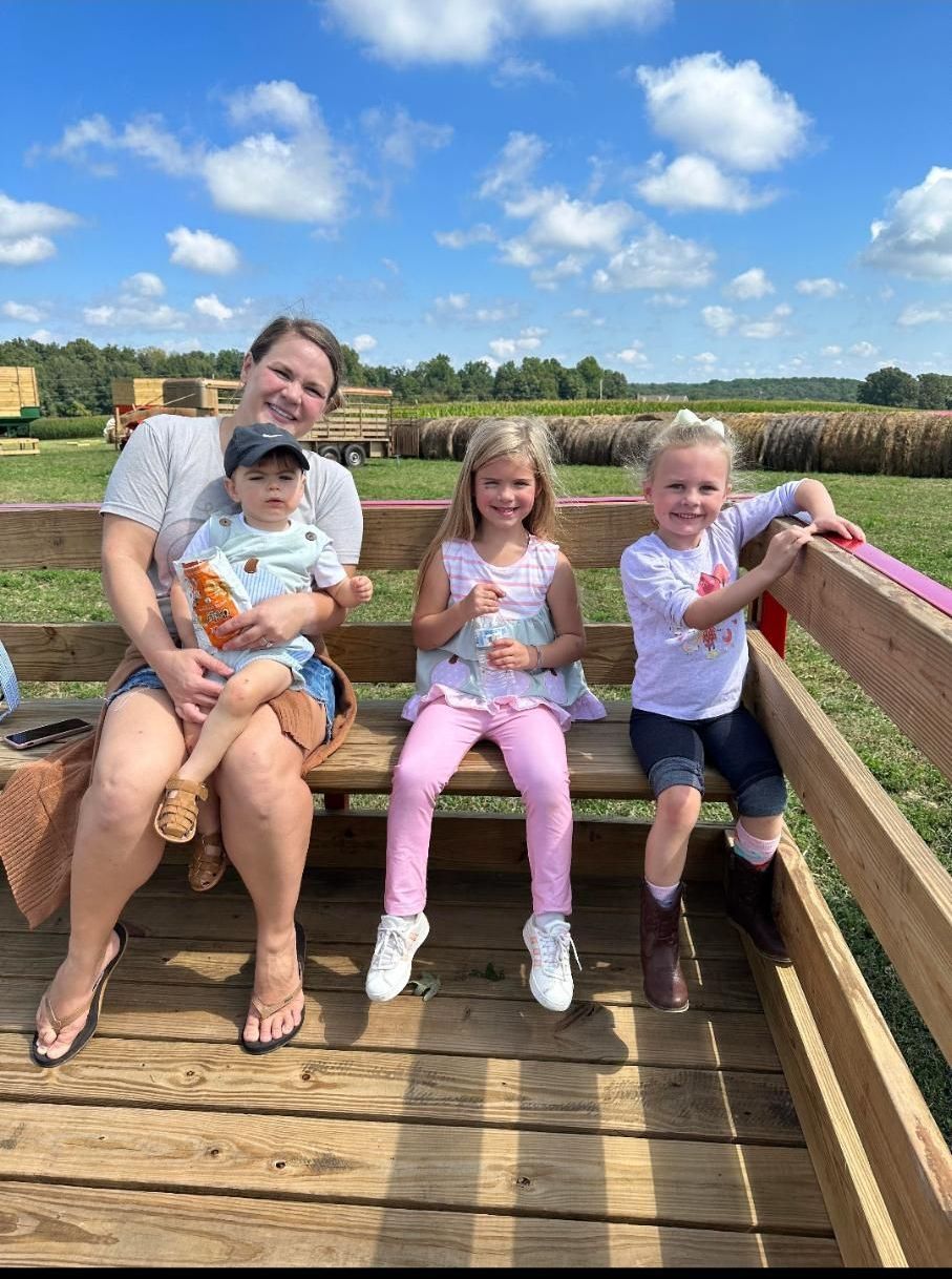 A woman and three children are sitting on a wooden bench.