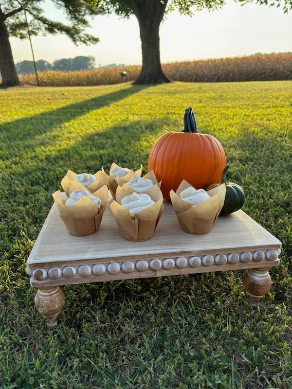 A wooden table with cupcakes and a pumpkin on it.