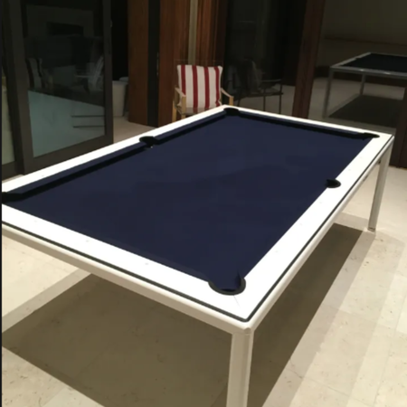 A modern pool table with a dark navy felt top and a sleek white frame, situated in a brightly lit indoor space.