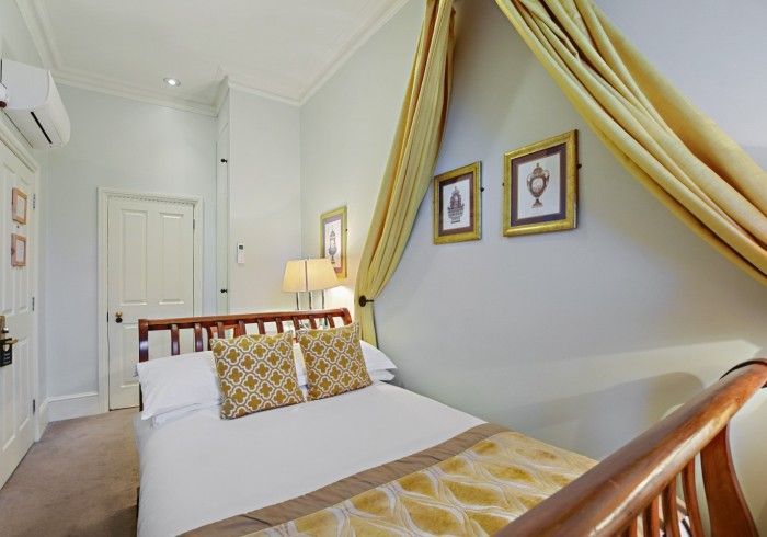 Bedroom with wooden bed, light walls, and yellow canopy. Two framed pictures above bed.
