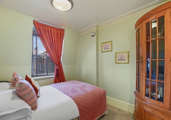 Bedroom with bed, red curtain, window, and wood cabinet. Green walls, white bedding, and artwork.