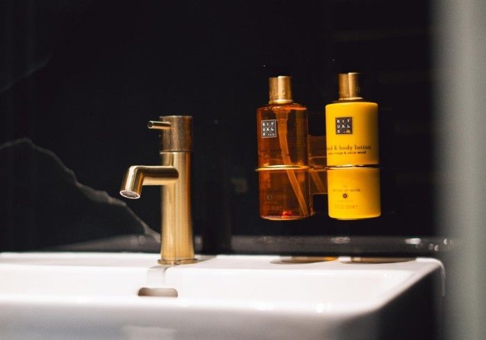 Gold faucet and bottles of shower gel in a modern bathroom.