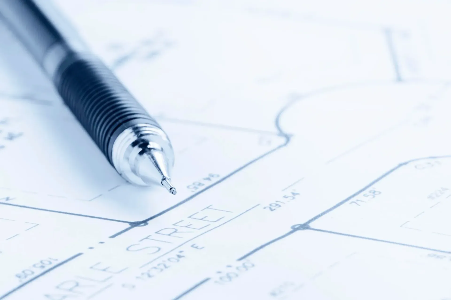 Pen resting on a detailed blueprint, likely a street map, with black lines and numbers.