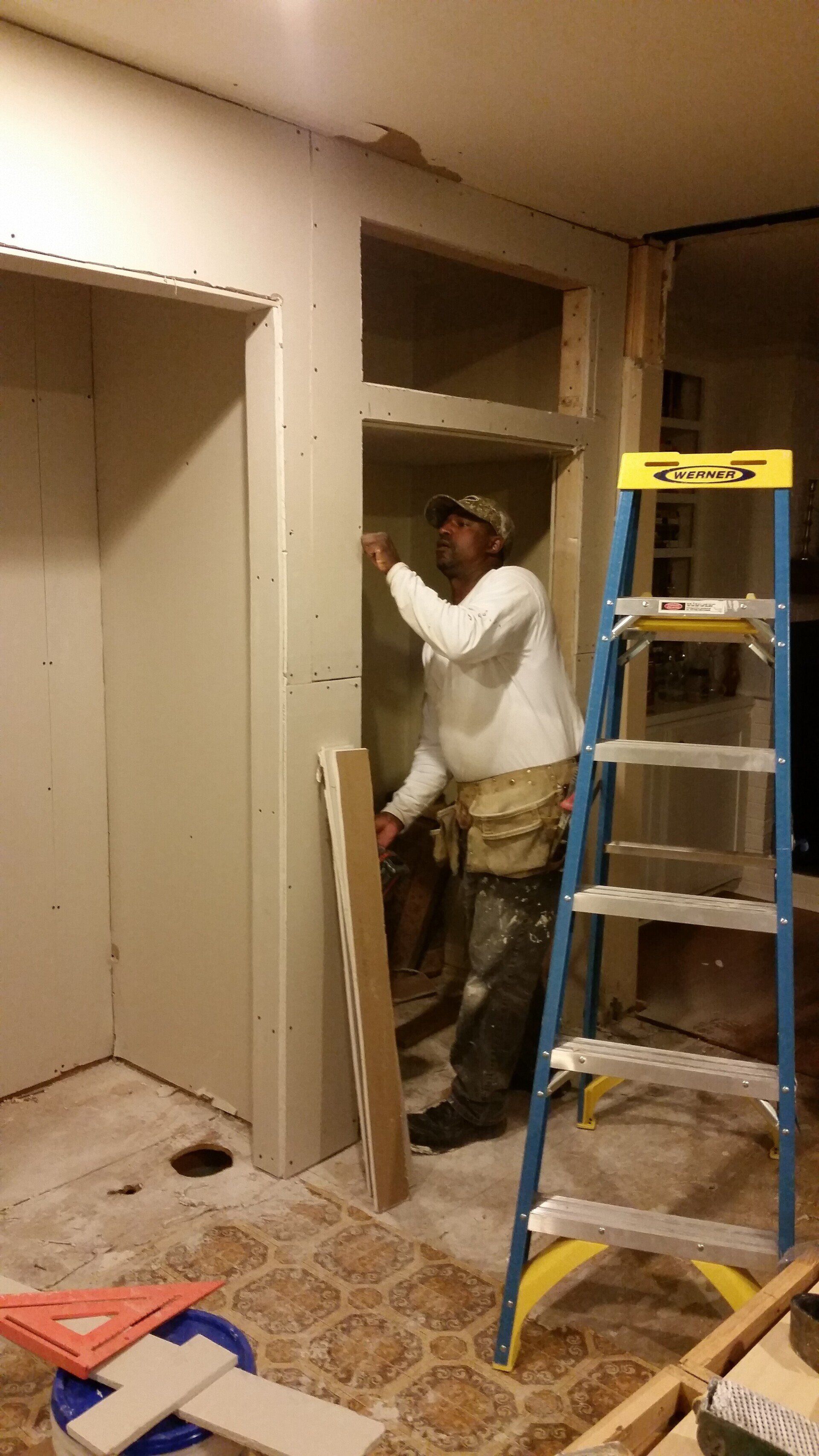 A man is standing next to a ladder in a room.