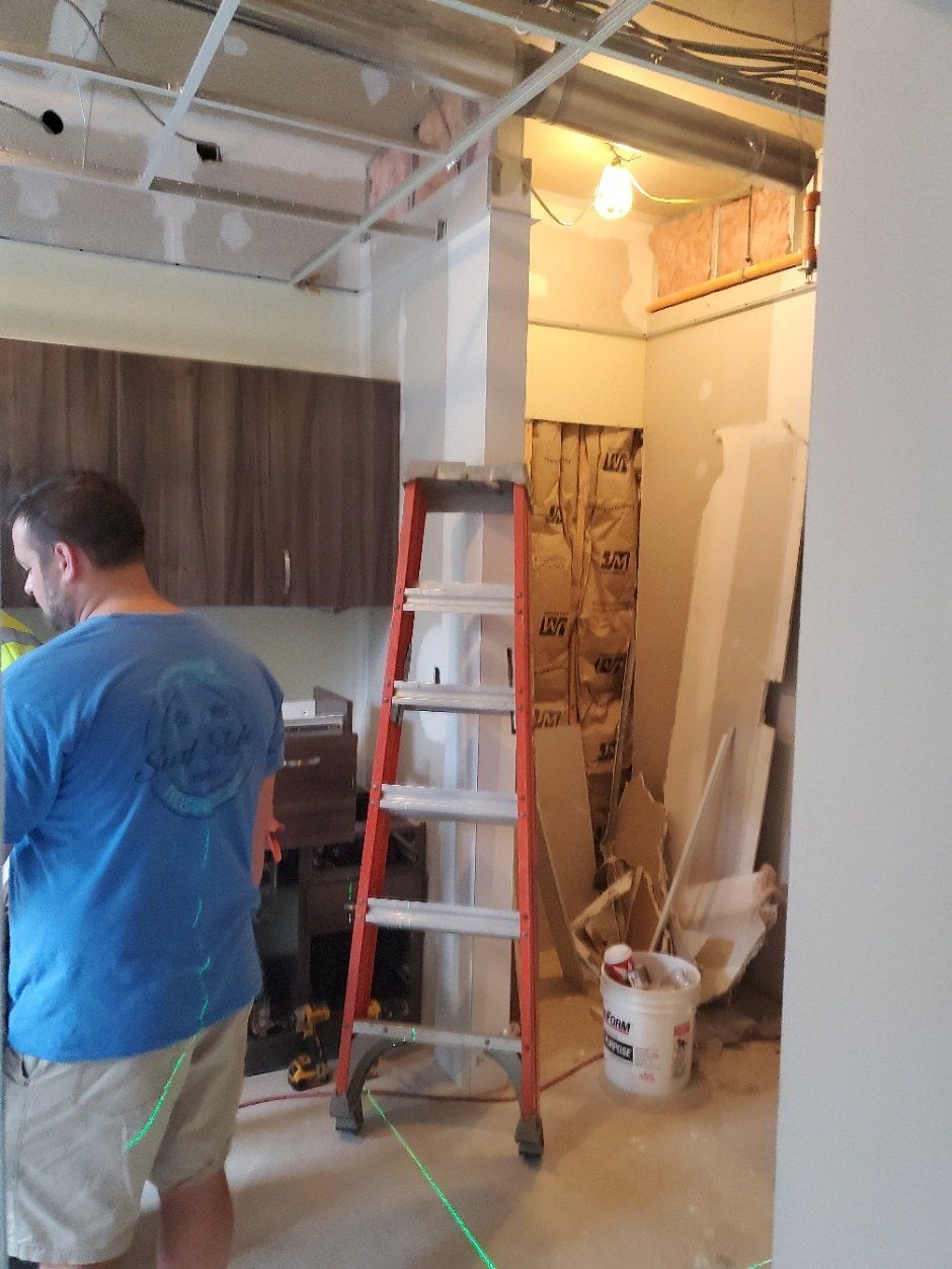 A man in a blue shirt is standing next to a ladder