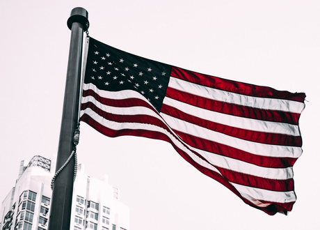 An american flag is flying on a pole in front of a building.