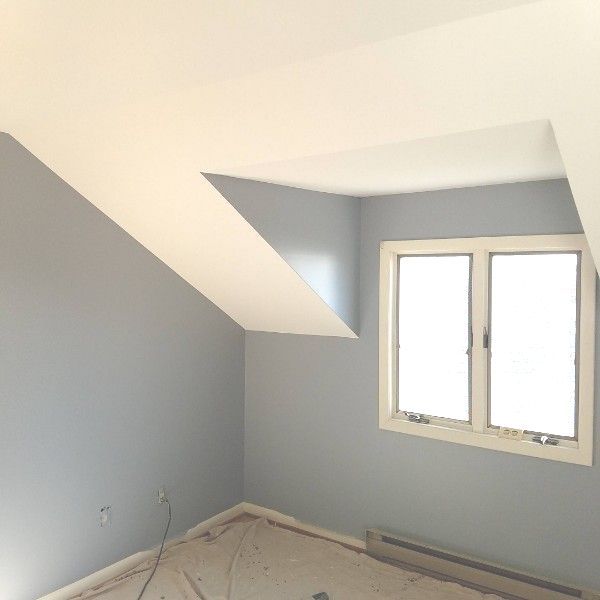 A room with a slanted ceiling and two windows