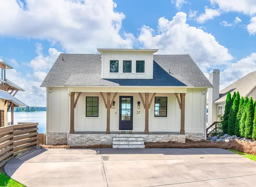 Modern coastal house with a porch, white exterior, and ocean view under a blue sky