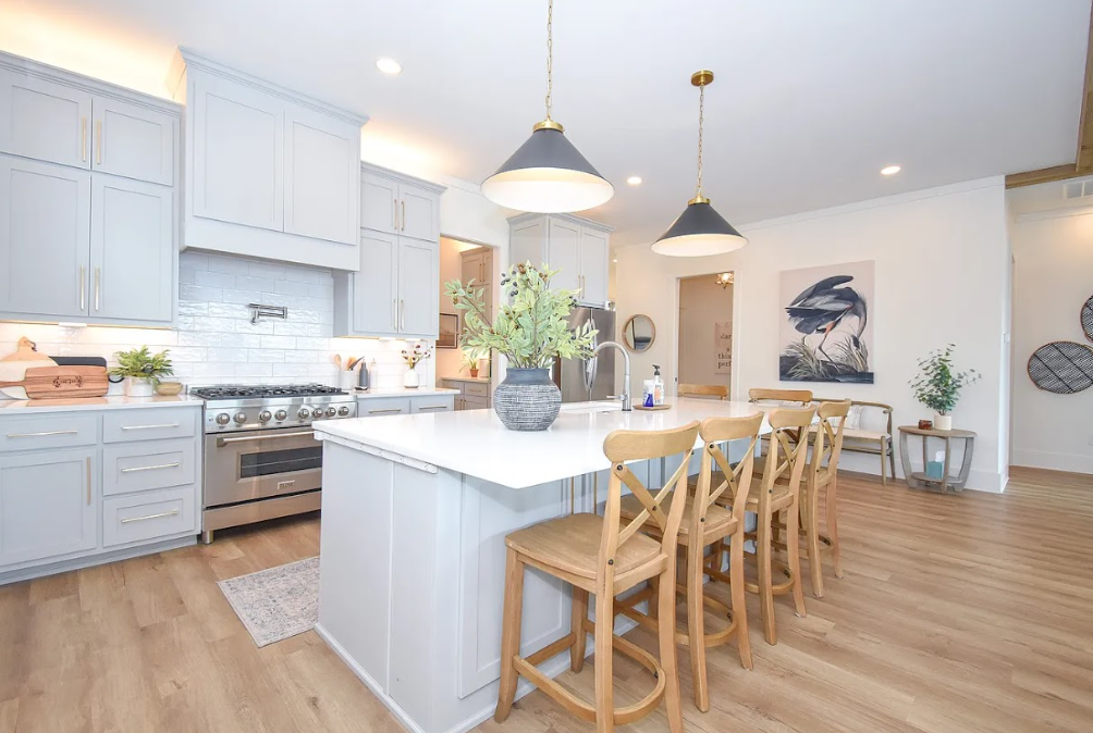 Bright modern kitchen with white cabinets, island seating, and wood floors
