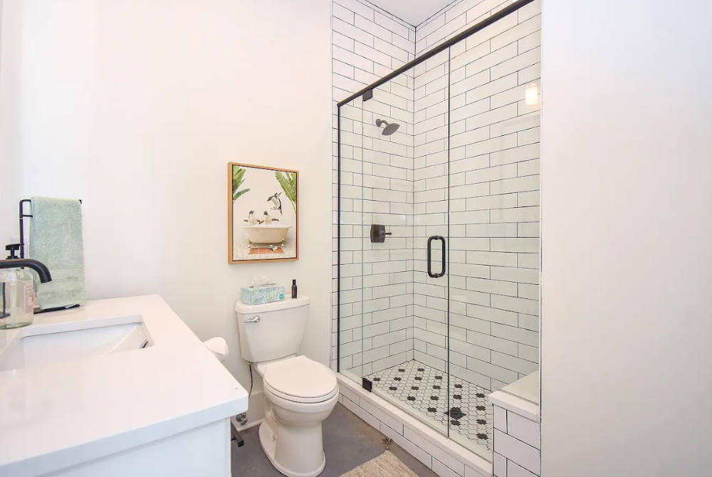 Small white bathroom with vanity, toilet, and glass-enclosed shower with subway tile.