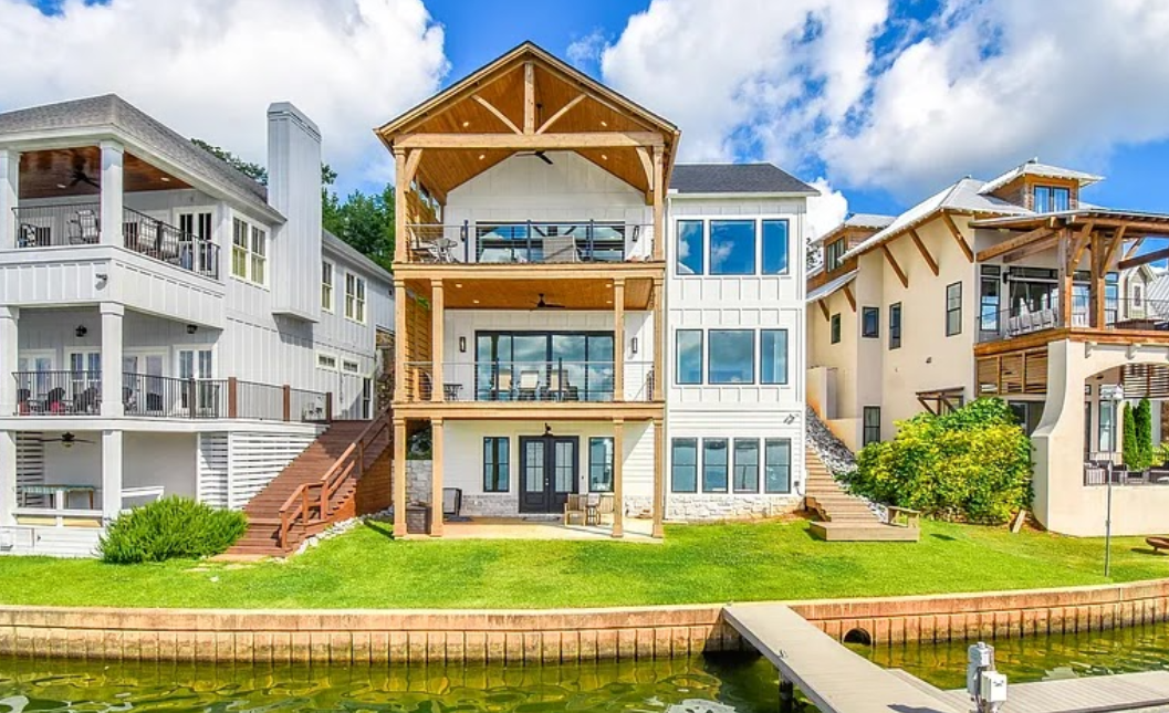 Waterfront row of modern homes with balconies and docks under a bright blue sky