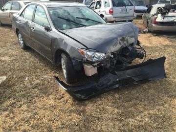 Gray sedan with severe front-end damage parked in a lot after a crash
