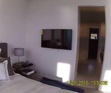 A bedroom with a bed and a flat screen tv on the wall.