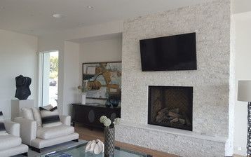 A living room with a fireplace and a flat screen tv on the wall.