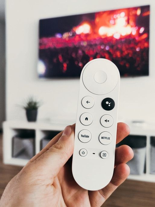 A person is holding a remote control in front of a television.