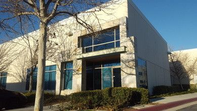 A large white building with a lot of windows and a tree in front of it.