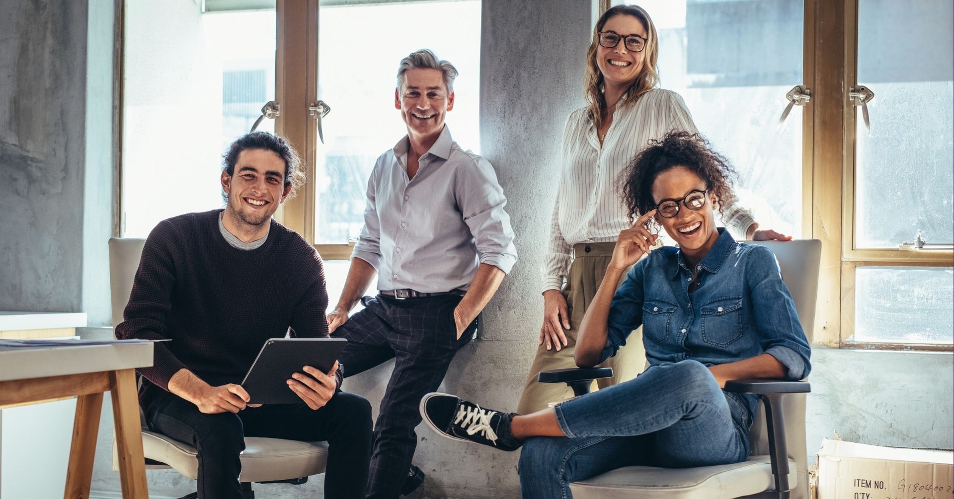 Confident and aligned small business team smiling together in a bright workspace, representing the r
