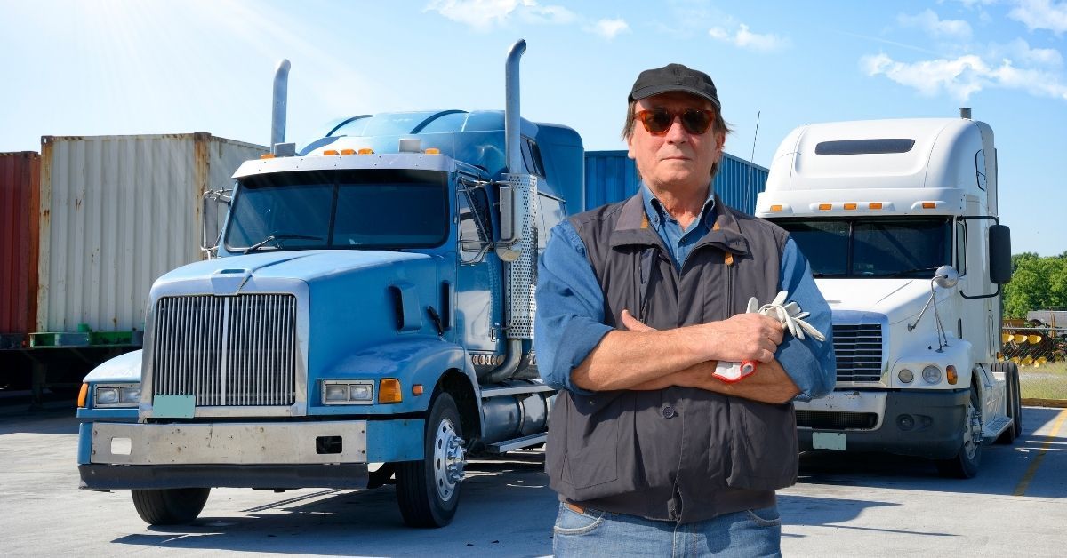 Confident transport business owner standing in front of his truck fleet, representing Australian SME