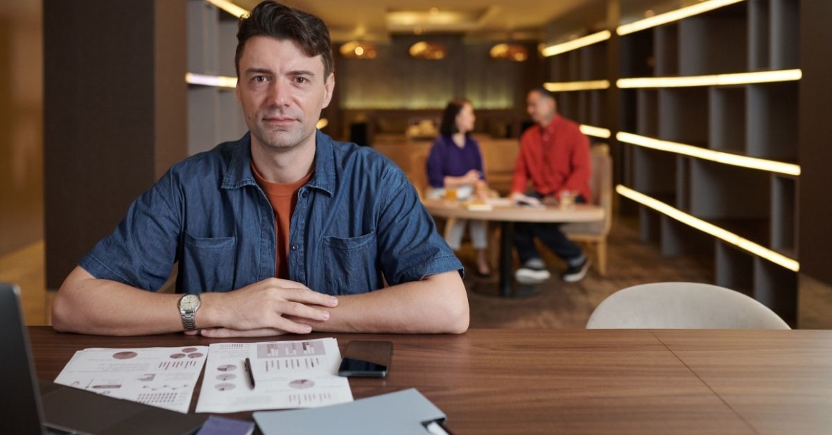 Focused Australian business owner sitting at a table with financial reports, reflecting on moving fr