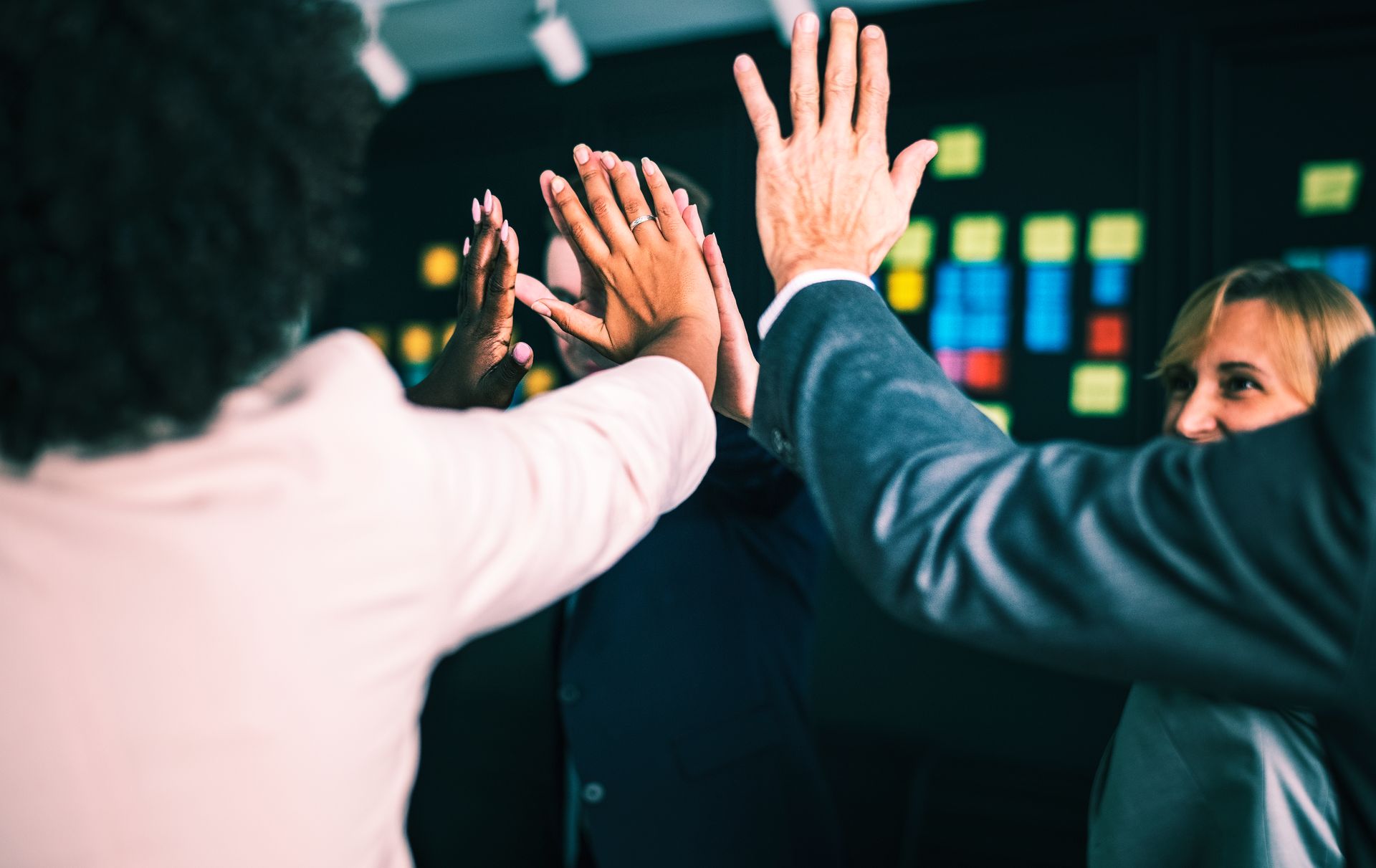 Business team giving a group high five in a collaborative workspace