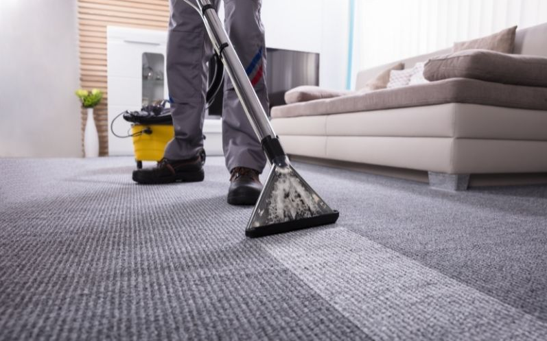 Carpet cleaning nozzle vacuuming a gray carpet, leaving a clean strip behind