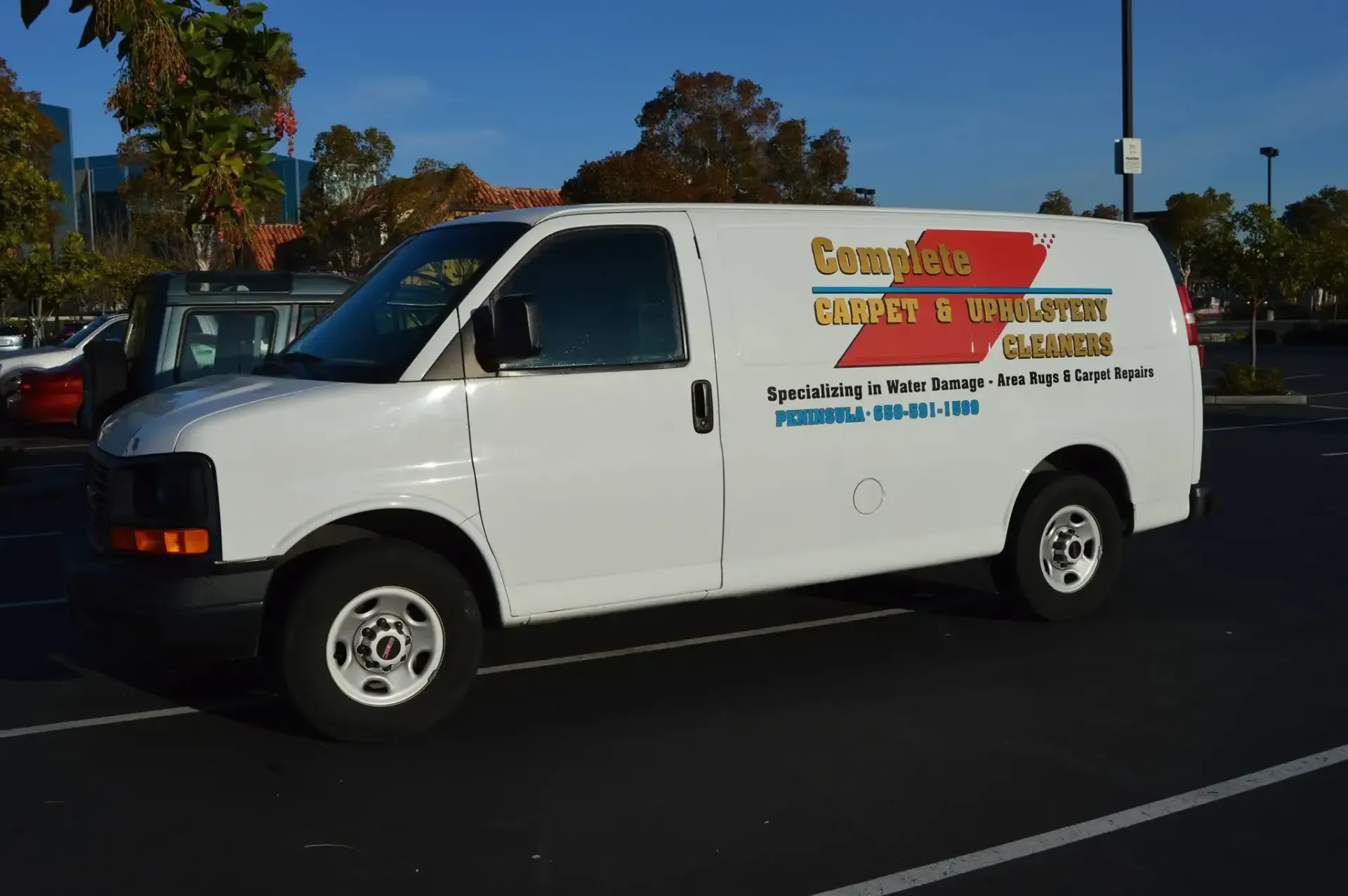 White utility van with company logo parked in a lot on a sunny day