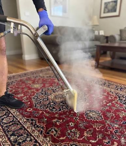 Person vacuuming a rug with a red upright vacuum cleaner indoors