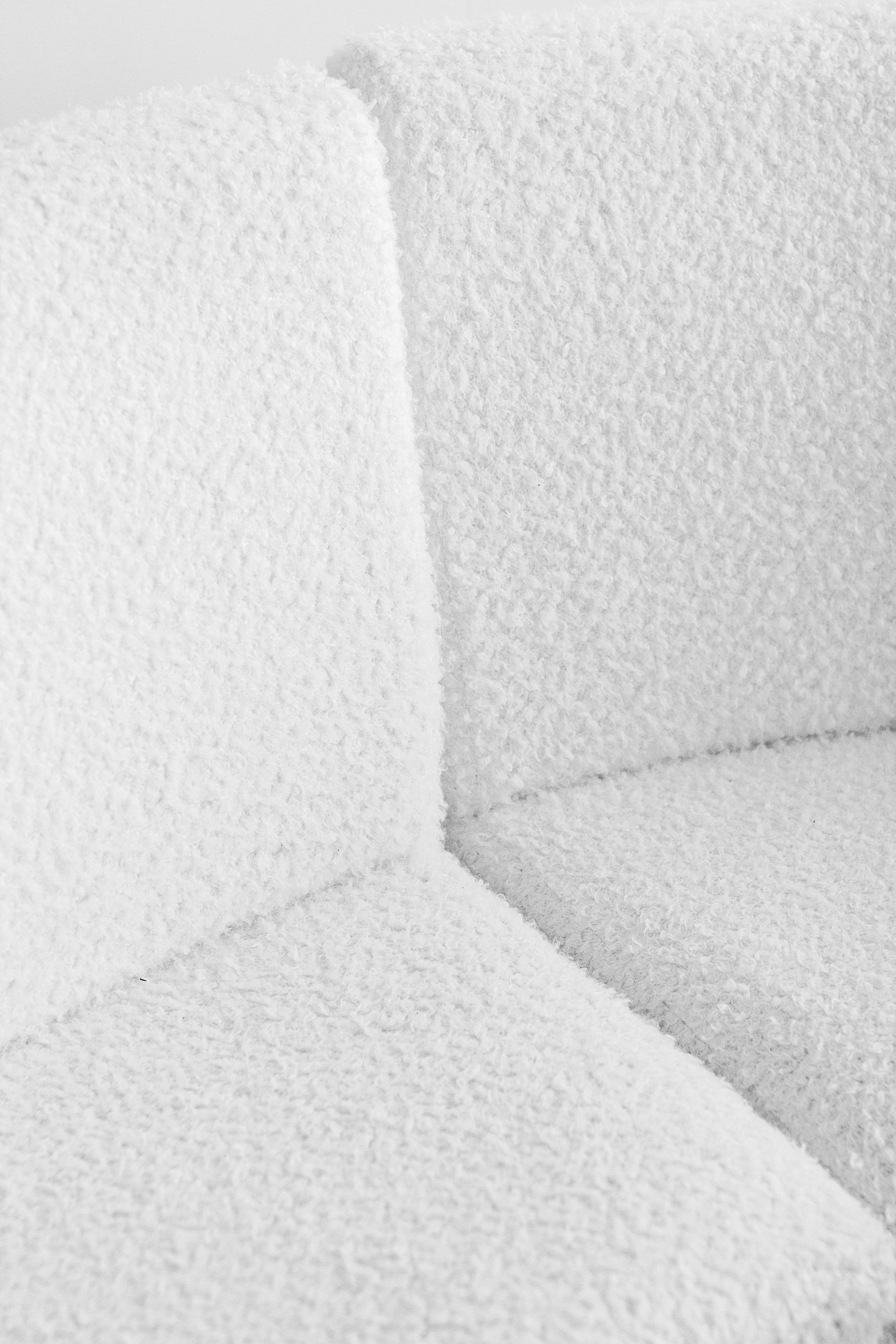Close-up of a white textured couch corner with soft shadows.