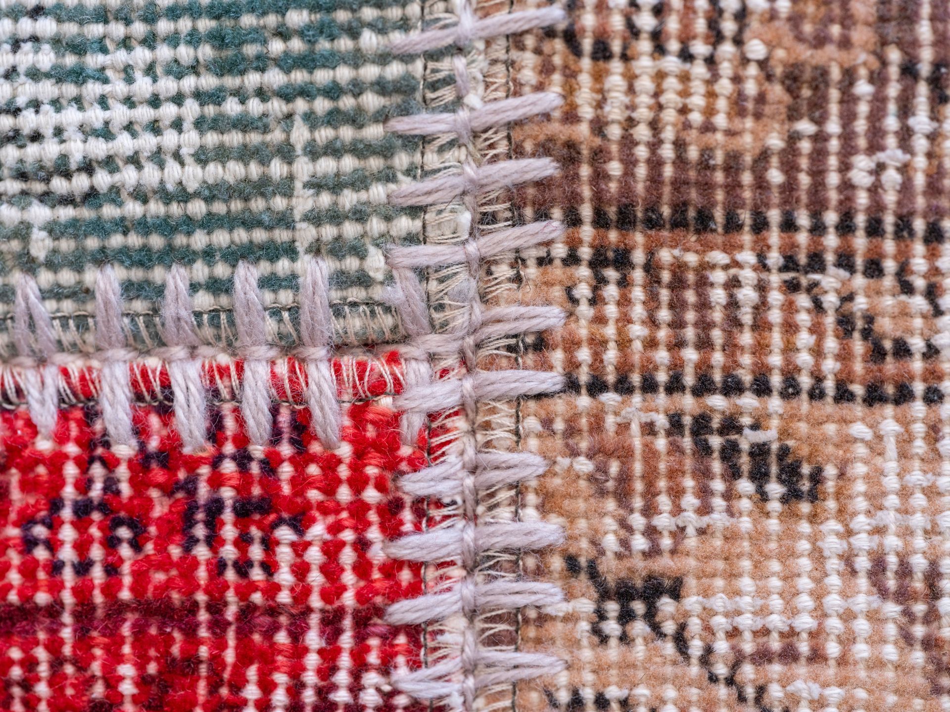 Close-up of a woven fabric with red, green, brown, and white stitched squares