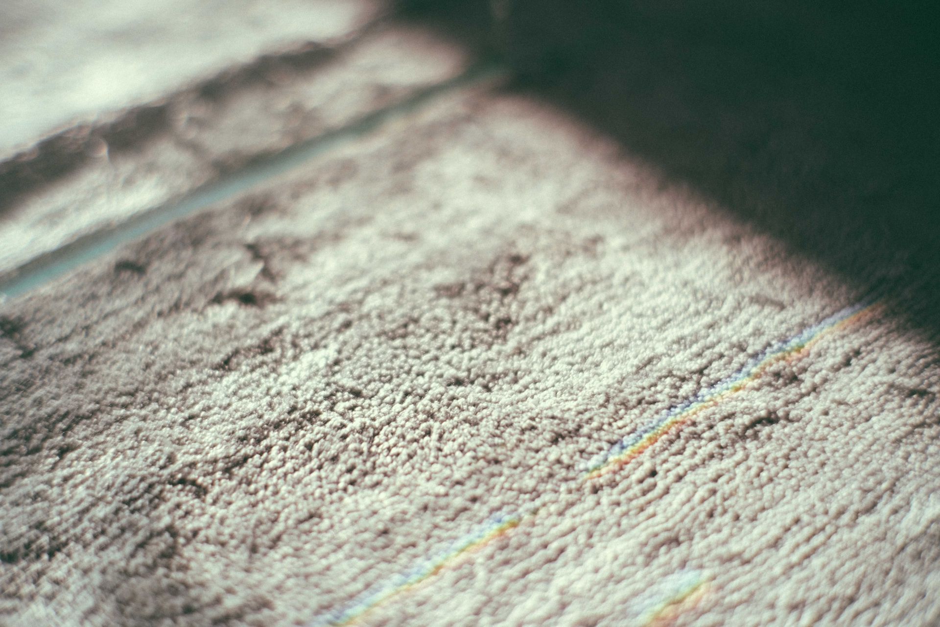 Close-up of a textured light gray surface with soft shadows and diagonal light bands