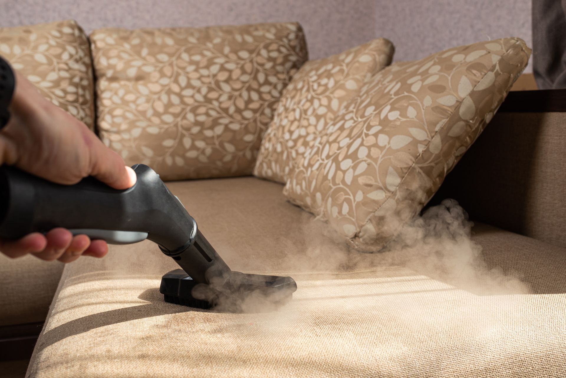 Person vacuuming a floral carpet with a yellow canister vacuum and gray floor head