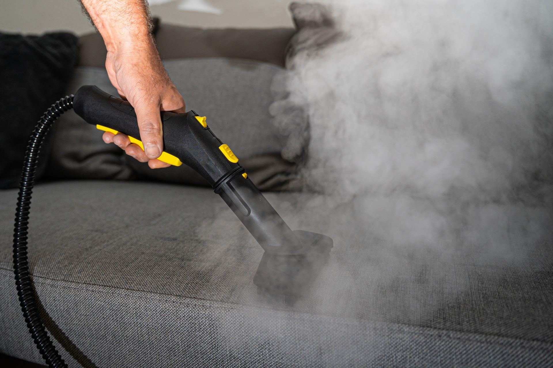 Person holding a yellow toy vacuum on a patterned rug