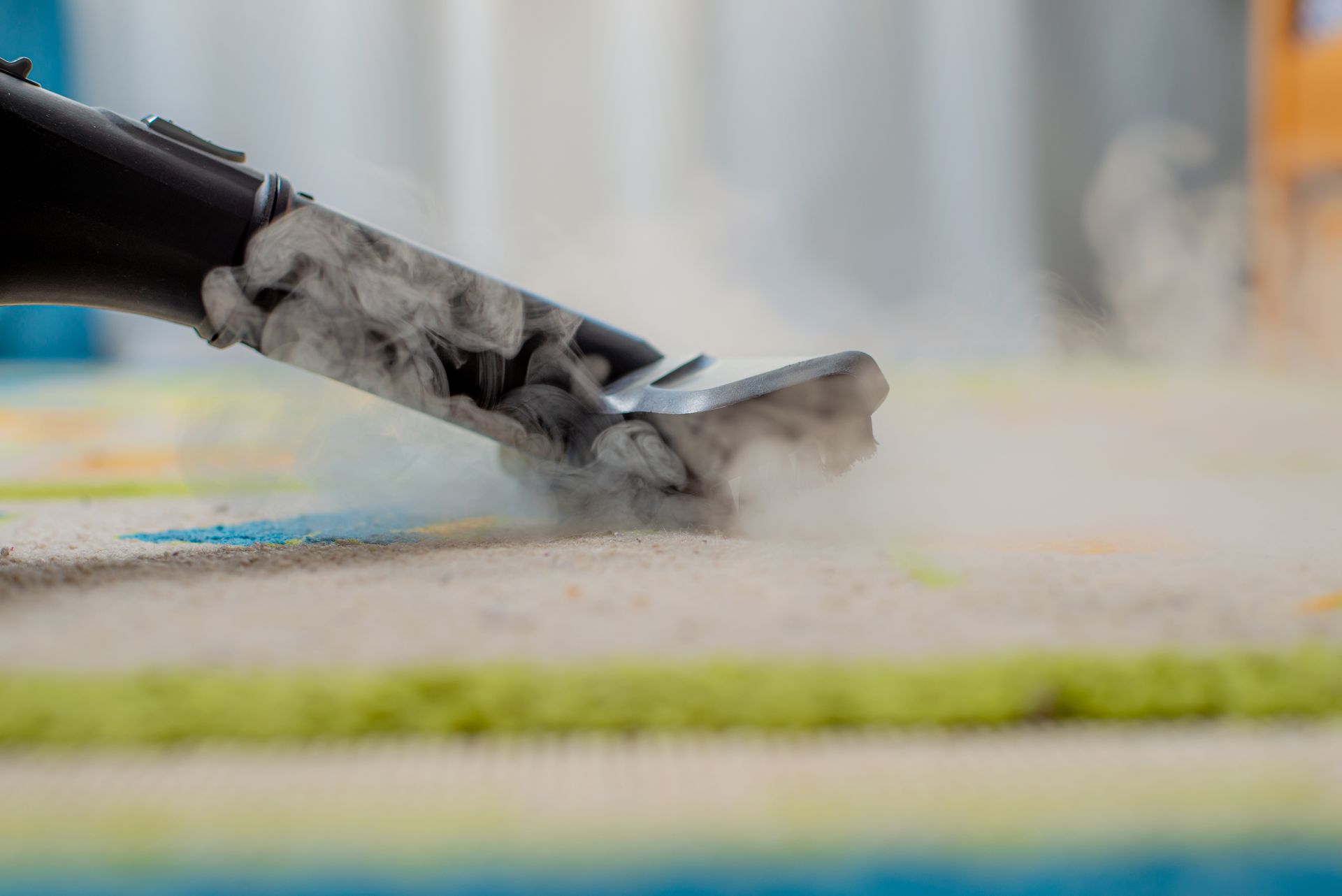 Person vacuuming a wooden floor with a black upright vacuum cleaner